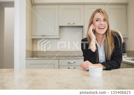 Woman leaning on marble countertop in kitchen holding smartphone and white coffee cup, copy space Woman leaning on marble countertop in kitchen holding smartphone and white coffee cup, copy space 135406825