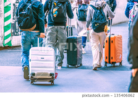 日本東京的城市景觀，以及遊客拖著行李箱的場景。外國遊客正從銀座線澀谷車站前往宮山坂下十字路口。 135406862