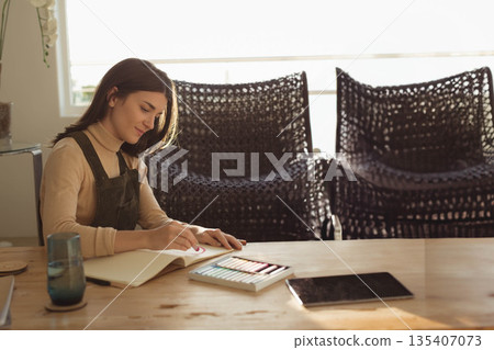 Female artist drawing circular shapes in sketchbook at home studio with colored pencils, copy space Female artist drawing circular shapes in sketchbook at home studio with colored pencils, copy space 135407073