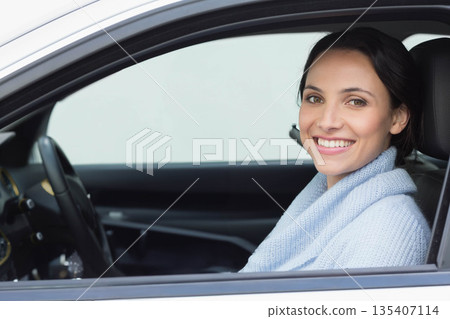 Woman gripping steering wheel wearing light blue sweater and smiling inside parked car, copy space Woman gripping steering wheel wearing light blue sweater and smiling inside parked car, copy space 135407114