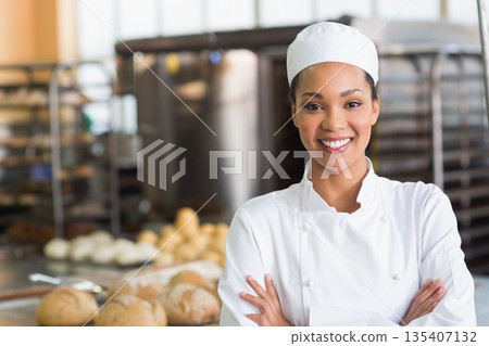 African American female baker smiling in bakery kitchen, bread loaves and mixer copy space African American female baker smiling in bakery kitchen, bread loaves and mixer copy space 135407132