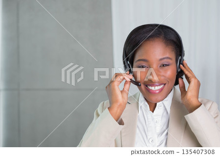 African American woman adjusting headset with microphone and smiling in call center, copy space African American woman adjusting headset with microphone and smiling in call center, copy space 135407308