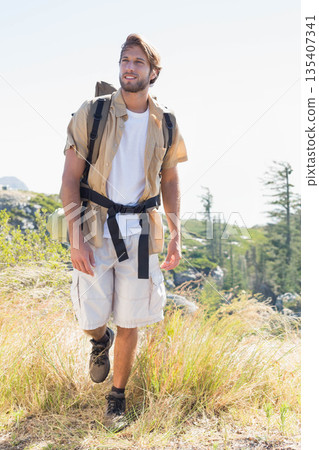 Male hiker striding through alpine meadow wearing hiking boots backpack with rolled sleeping pad Male hiker striding through alpine meadow wearing hiking boots backpack with rolled sleeping pad 135407341