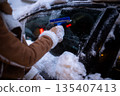 Scraping Frozen Windshield in Urban Winter Scene 135407413