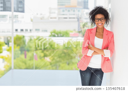 African American woman leaning on wall in office hallway wearing black glasses, copy space African American woman leaning on wall in office hallway wearing black glasses, copy space 135407618