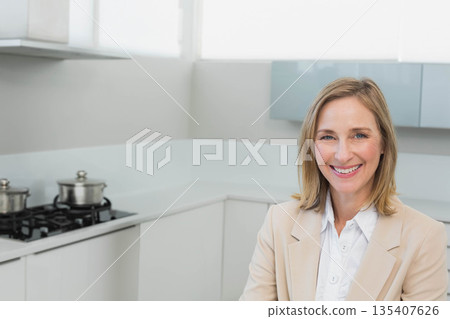 Woman smiling while standing in home kitchen by gas cooktop and stainless steel pots, copy space 135407626