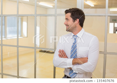 Man leaning against metal-framed partition in office, wearing shirt and striped tie, copy space Man leaning against metal-framed partition in office, wearing shirt and striped tie, copy space 135407676