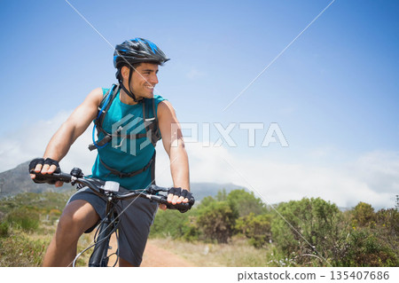 Male cyclist riding mountain bike along dusty dirt trail wearing helmet, hydration pack, gloves Male cyclist riding mountain bike along dusty dirt trail wearing helmet, hydration pack, gloves 135407686