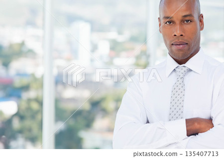 African American man standing before window with blurred skyline in office wearing tie, copy space 135407713