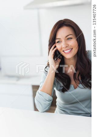 Professional woman talking on smartphone at office desk with computer monitor, copy space 135407726