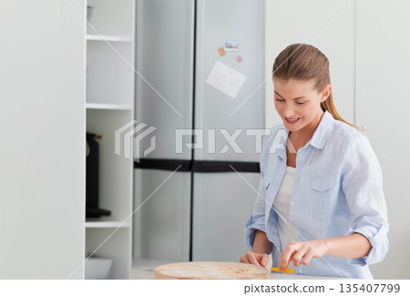 Woman slicing yellow bell pepper with kitchen knife on cutting board in kitchen, copy space Woman slicing yellow bell pepper with kitchen knife on cutting board in kitchen, copy space 135407799