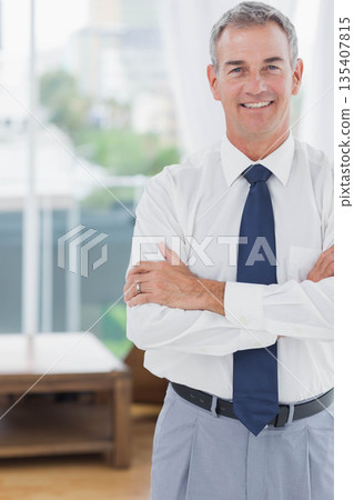 Businessman standing with arms folded in office lounge showing coffee table and bench, copy space Businessman standing with arms folded in office lounge showing coffee table and bench, copy space 135407815