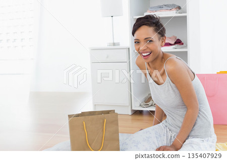 African American woman kneeling on bedroom floor with brown, pink shopping bags, copy space African American woman kneeling on bedroom floor with brown, pink shopping bags, copy space 135407929