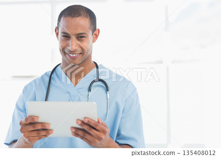 African American male healthcare worker holding tablet and smiling in clinic with stethoscope African American male healthcare worker holding tablet and smiling in clinic with stethoscope 135408012