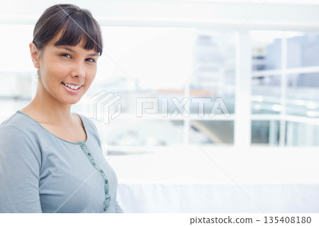 Woman sitting on white sofa in lounge overlooking city skyline through glass railing, copy space Woman sitting on white sofa in lounge overlooking city skyline through glass railing, copy space 135408180