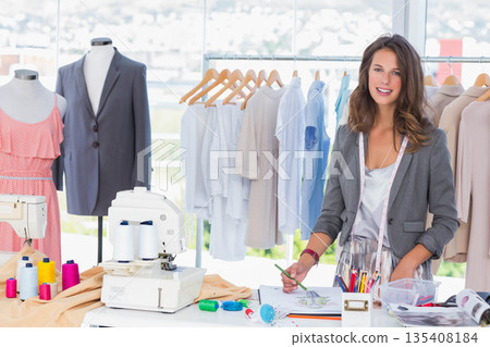 Woman wearing blazer sketching design with pencils, measuring tape in fashion studio, copy space 135408184
