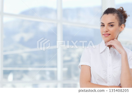 African American woman wearing white shirt standing in room by window viewing mountains, copy space 135408205