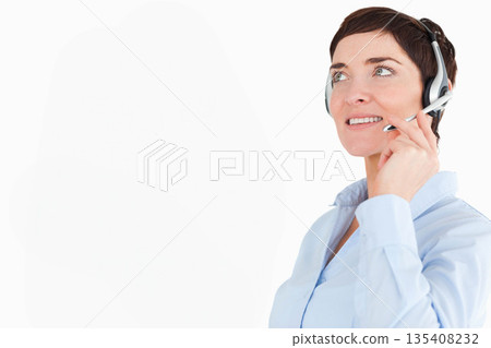 Female customer service representative tilting head and smiling with headset in office, copy space 135408232