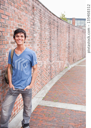 Man leaning against red brick wall beside urban brick walkway carrying green backpack, copy space 135408312