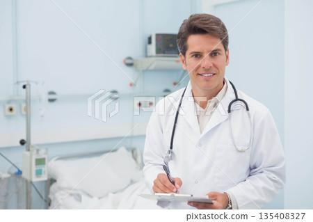 Male physician wearing white coat and stethoscope writing on clipboard in patient room, copy space Male physician wearing white coat and stethoscope writing on clipboard in patient room, copy space 135408327