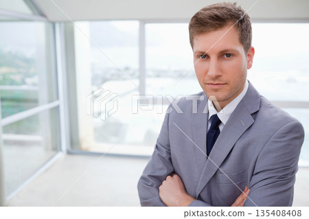 Male standing in office space overlooking waterfront wearing grey suit and dark tie, copy space 135408408