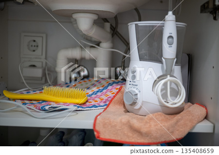 Home bathroom storage with electric oral irrigator towel and brush under sink in organized cabinet space Home bathroom storage with electric oral irrigator towel and brush under sink in organized cabinet space 135408659