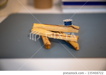 Minimal still life with wooden sticks and blue thread spool creating calm handmade craft composition Minimal still life with wooden sticks and blue thread spool creating calm handmade craft composition 135408722