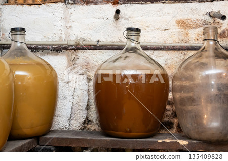 View of old fashioned wine cellar with glass storage for wine during fermentation process. View of old fashioned wine cellar with glass storage for wine during fermentation process. 135409828