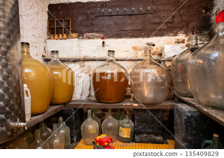 View of old fashioned wine cellar with glass storage for wine during fermentation process. View of old fashioned wine cellar with glass storage for wine during fermentation process. 135409829