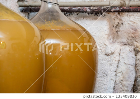 View of old fashioned wine cellar with glass storage for wine during fermentation process. View of old fashioned wine cellar with glass storage for wine during fermentation process. 135409830
