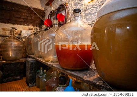 View of old fashioned wine cellar with glass storage for wine during fermentation process. View of old fashioned wine cellar with glass storage for wine during fermentation process. 135409831