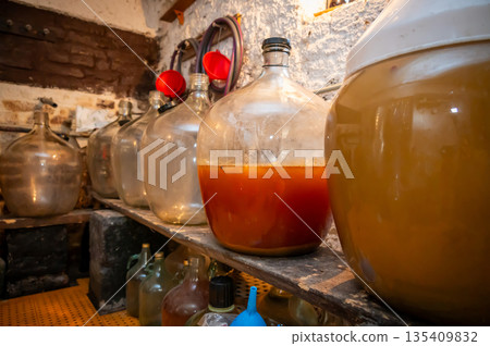 View of old fashioned wine cellar with glass storage for wine during fermentation process. View of old fashioned wine cellar with glass storage for wine during fermentation process. 135409832