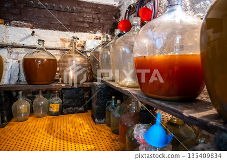 View of old fashioned wine cellar with glass storage for wine during fermentation process. View of old fashioned wine cellar with glass storage for wine during fermentation process. 135409834