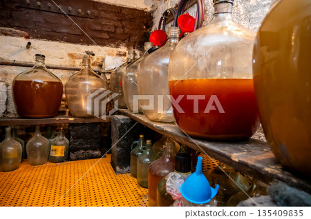 View of old fashioned wine cellar with glass storage for wine during fermentation process. View of old fashioned wine cellar with glass storage for wine during fermentation process. 135409835