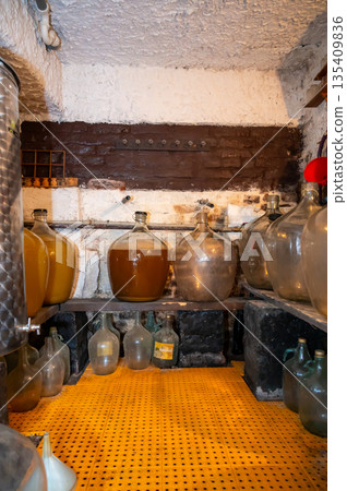 View of old fashioned wine cellar with glass storage for wine during fermentation process. View of old fashioned wine cellar with glass storage for wine during fermentation process. 135409836