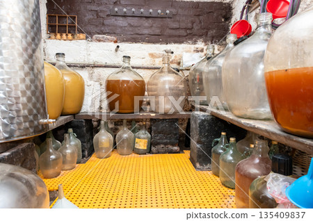 View of old fashioned wine cellar with glass storage for wine during fermentation process. View of old fashioned wine cellar with glass storage for wine during fermentation process. 135409837