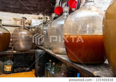 View of old fashioned wine cellar with glass storage for wine during fermentation process. View of old fashioned wine cellar with glass storage for wine during fermentation process. 135409838