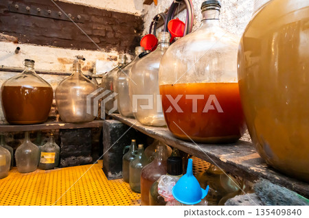 View of old fashioned wine cellar with glass storage for wine during fermentation process. View of old fashioned wine cellar with glass storage for wine during fermentation process. 135409840