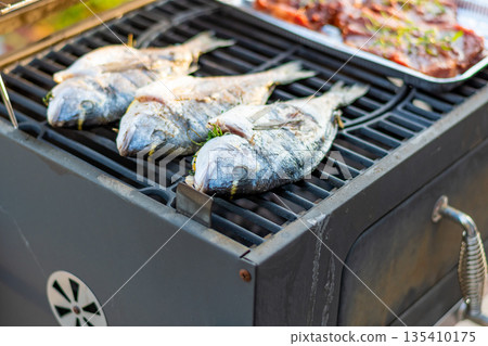 Sea bream dorado fish placed on the grill. Fresh sea food with herb and lemon. Summer bbq Sea bream dorado fish placed on the grill. Fresh sea food with herb and lemon. Summer bbq 135410175