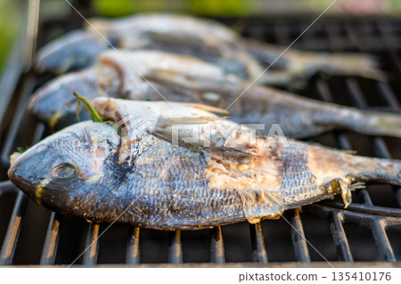 Sea bream dorado fish placed on the grill. Fresh sea food with herb and lemon. Summer bbq Sea bream dorado fish placed on the grill. Fresh sea food with herb and lemon. Summer bbq 135410176