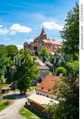 Outdoor view of Pernstejn castle near the Nedvedice village, Czech Republic. Fairytale castle on hill during summer day. Big stone walls and towers. Outdoor view of Pernstejn castle near the Nedvedice village, Czech Republic. Fairytale castle on hill during summer day. Big stone walls and towers. 135410243
