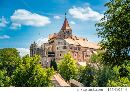 Outdoor view of Pernstejn castle near the Nedvedice village, Czech Republic. Fairytale castle on hill during summer day. Big stone walls and towers. Outdoor view of Pernstejn castle near the Nedvedice village, Czech Republic. Fairytale castle on hill during summer day. Big stone walls and towers. 135410244