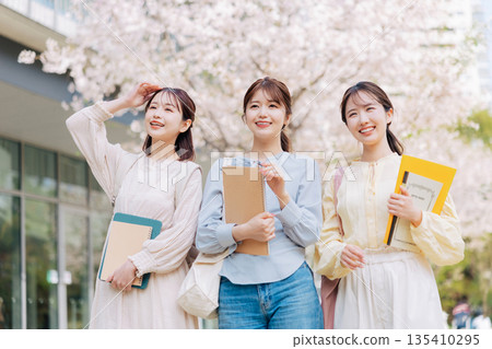 Three female college students walking on a cherry blossom campus Three female college students walking on a cherry blossom campus 135410295