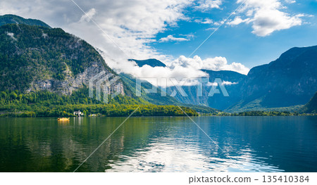 Hallstatt see lake near the Salzburg city. View of lake and big mountains in background. Cloudy weather, big clouds and mist over lake. Hallstatt see lake near the Salzburg city. View of lake and big mountains in background. Cloudy weather, big clouds and mist over lake. 135410384