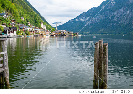 Hallstatt Village and Hallstatter See lake in Austria. Scenery with famous old church near the lake. Clouds and mist over the mountains in background. Famous tourist destination. 135410390
