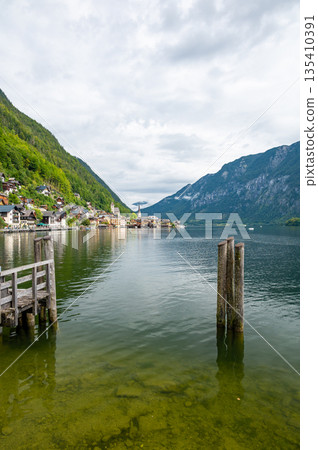 Hallstatt Village and Hallstatter See lake in Austria. Scenery with famous old church near the lake. Clouds and mist over the mountains in background. Famous tourist destination. 135410391