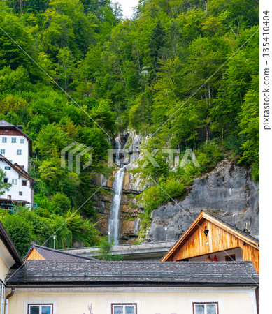 Waterfall at Hallstat city, Austria. Fresh water stream above city roofs. Waterfall at Hallstat city, Austria. Fresh water stream above city roofs. 135410404