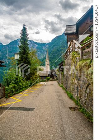Famous Hallstatt city panorama with typical church near the Hallstatter see. Dramatic clouds on the sky. Famous tourist destination in Austria. 135410417