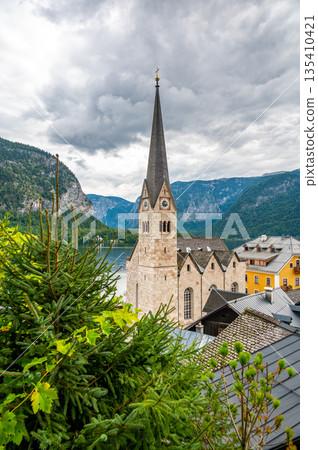 Famous Hallstatt city panorama with typical church near the Hallstatter see. Dramatic clouds on the sky. Famous tourist destination in Austria. 135410421