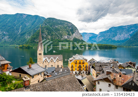 Famous Hallstatt city panorama with typical church near the Hallstatter see. Dramatic clouds on the sky. Famous tourist destination in Austria. Famous Hallstatt city panorama with typical church near the Hallstatter see. Dramatic clouds on the sky. Famous tourist destination in Austria. 135410423